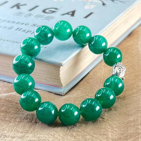 Green beaded bracelet with a silver Buddha charm on a book